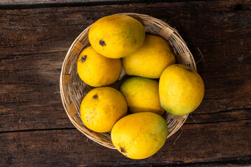 Ripe mango tropical fruit in basket on wooden table at mangoes farm