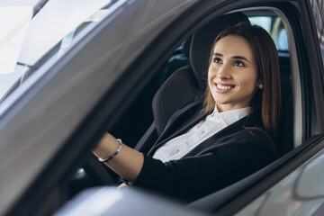 Saleswoman Smiling while Sitting in New Car at Dealership