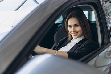 Fototapeta premium Businesswoman smiling while driving a new car in a dealership