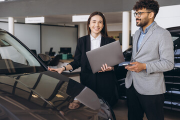 Car dealer showing a new car to a client in a dealership