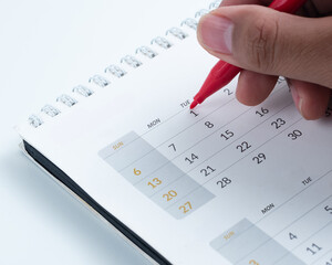 Hand marking date on calendar with red pen &ndash; planning, scheduling, and time management concept for business and personal use