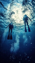 Two Scuba Divers Ascending in Deep Blue Ocean Waters from Low Angle Underwater View with Bubbles