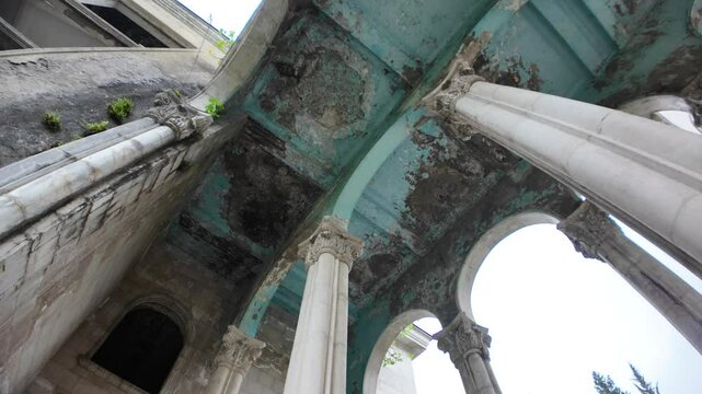 Crumbling turquoise ceiling and weathered columns evoke a haunting atmosphere in the abandoned Medea Sanatorium, highlighting the decay of a once-popular Soviet-era spa in Tskaltubo, Georgia
