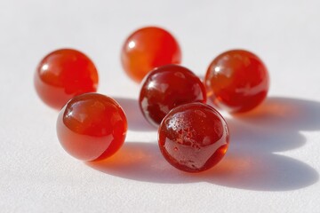 Polished, red gemstone spheres.  Close-up view of several round, polished red gemstones, likely carnelian, arranged loosely on a white surface