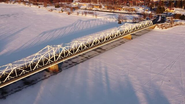 Aerial following snowy bridge over frozen river, Tornio, Finland