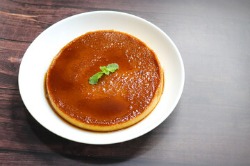 Delicious caramel custard with a glossy caramel top, served on a white plate. Perfectly lit, smooth texture, and minimal background. ideal for menus, blogs, packaging, or dessert features. Copy space