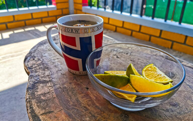 Cup with ginger tea and lemon orange lime citrus fruits.