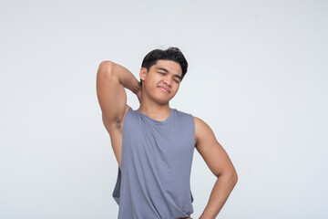 A young Southeast Asian man touches his neck and grimaces slightly, showing mild discomfort or...