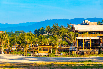 Sun beach sand people surfer waves palms Puerto Escondido Mexico.