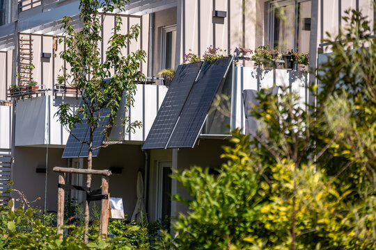 Modernes Balkonkraftwerk mit Solarpanels an einem Mehrfamilienhaus im Sommer, nachhaltige Energiegewinnung im urbanen Raum, gr&uuml;nes Wohnen und erneuerbare Energien.