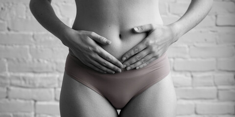 Woman's lower abdomen and hands gently resting on it against a brick background, showcasing a calm and serene mood, suggesting wellness or self-care