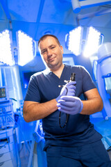 Surgeon readying for surgery. Surgeon in scrubs holds a surgical instrument in a brightly lit...