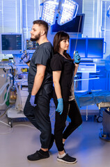 Surgeons in surgical gear. Two healthcare professionals hold surgical instruments back-to-back in a...