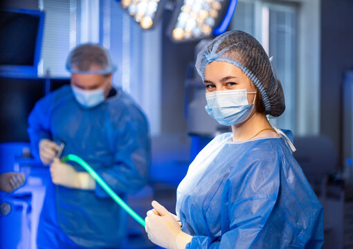 Surgeons ready for operation. Two health care workers, wearing surgical scrubs and masks, get ready for an operation in a modern operating room.