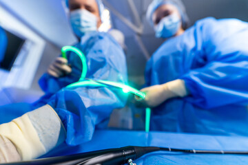 Surgeons operate in a sterile room. Surgeons in blue scrubs work diligently in a modern operating...