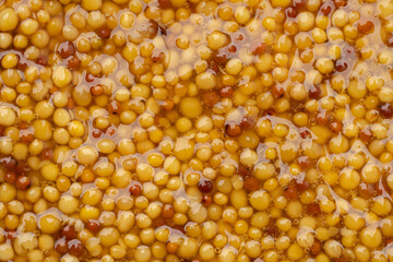 French Dijon mustard in a metal spoon, top view on mustard grains background. Gastronomy concept,...