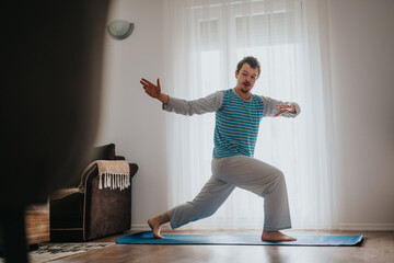 Individual performing yoga indoors on a mat, wearing casual attire. The setting suggests focus on...