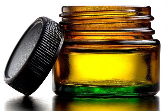 Clear glass jar containing golden substance with black lid positioned on reflective surface