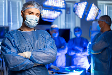 Surgeon gets ready in OR. A surgeon stands confidently in full scrubs and mask before a surgical...