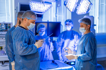 Surgeons in the OR. Surgeons perform a procedure in a well-equipped operating room, focused under...
