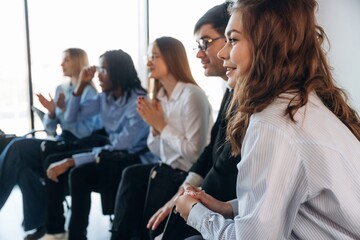 Fototapeta premium Looking to the side, smiling. Group of young business people are in conference room