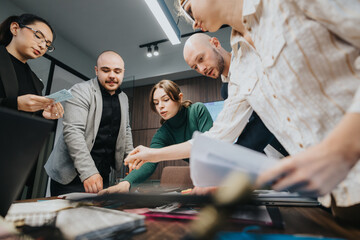 Employees discussing and analyzing documents as they collaborate around a table in a professional...