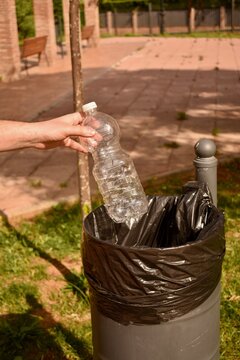 Disposing plastic in trash can outdoors. Sustainable behavior in public space.

