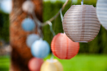 Many colorful lanterns, paper lanterns hang festively in the garden. For festival, party, wedding