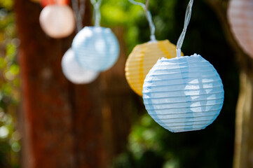 Many colorful lanterns, paper lanterns hang festively in the garden. For festival, party, wedding