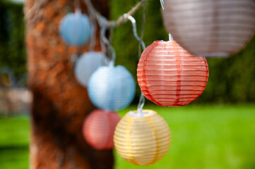 Many colorful lanterns, paper lanterns hang festively in the garden. For festival, party, wedding