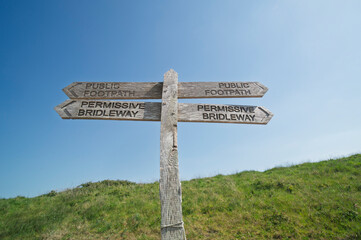 Permissive bridleway and footpath sign against a blue sky background