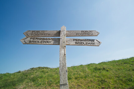 Permissive bridleway and footpath sign against a blue sky background