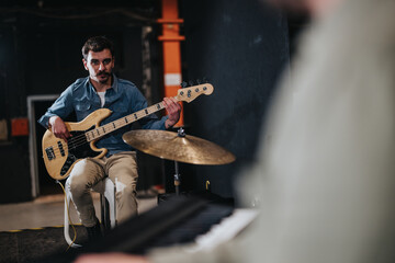 Musician rehearsing with electric bass guitar during a band practice in studio