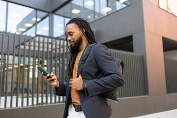 Cuban business man walking while using smartphone outdoors