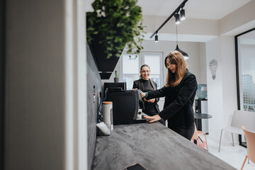 A pair of colleagues take a break to prepare coffee in a modern office kitchenette, showcasing...