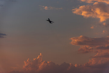 Scenic view of a vibrant sunset over mountains, airplane flying across the colorful sky.