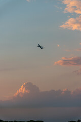 Scenic view of a vibrant sunset over mountains, airplane flying across the colorful sky.