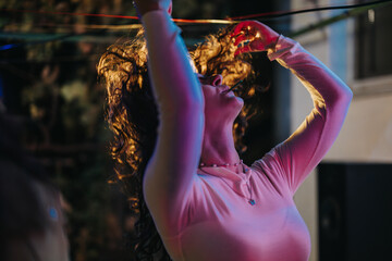 A vibrant depiction of a woman in motion under colorful lighting during a festive event. Capturing the joy of music, dance, and celebration on a spirited evening.