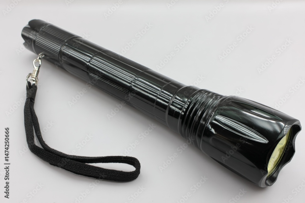 Poster black flashlight with textured grip and lanyard intended for outdoor and emergency use in low-light 