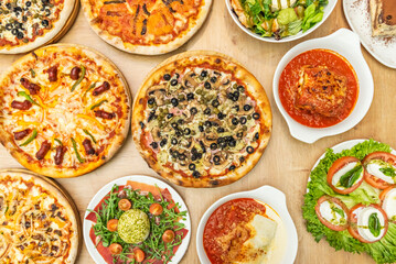 A table full of various pizzas and typical Italian dishes