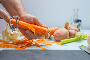 Hands of a cook cutting and peeling carrots, turnips and carrots on a table