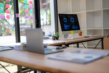 A computer monitor is on a desk with a laptop