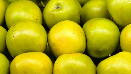 Close-up view of fresh, vibrant green apples arranged in a heap formation