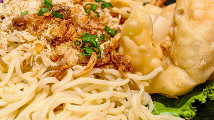 Delicious asian noodles with fried dumplings, crispy onions, and vibrant herbs