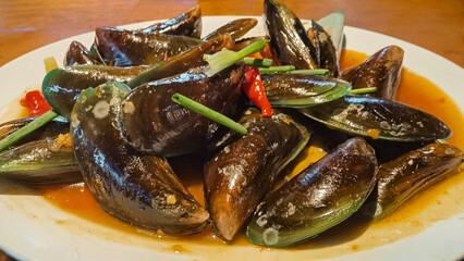 Delicious plate of steamed mussels with chili sauce and herbs for culinary enjoyment