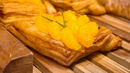 Delicious orange puff pastry on wooden surface for bakery shop concept