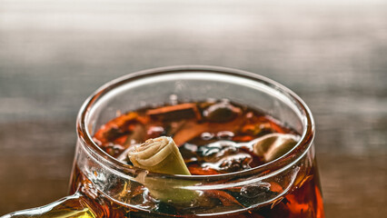 Refreshing herbal drink wedang uwuh in a glass, with lemongrass, cardamom, ginger, sappanwood, rock...