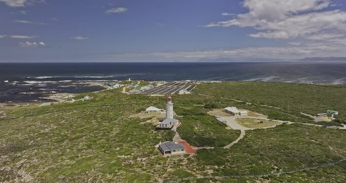 Gansbaai South Africa Aerial v15 flyover Birkenhead capturing the Danger Point Lighthouse standing on the green terrain and the scenic coastal landscape - Shot with Mavic 3 Pro Cine - Jan 8th 2024
