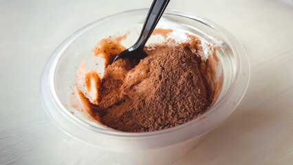 A close-up of chocolate ice cream with powder in a transparent bowl