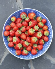 Fresh strawberries in blue bowl overhead shot on stone surface healthy eating summer fruit garden harvest ingredient